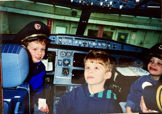 three boys in cockpit of plane